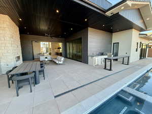 View of patio featuring ceiling fan, a pool with connected hot tub, and an outdoor kitchen / dining area