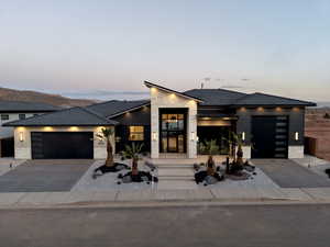 Modern home featuring stone siding, an attached garage, and driveway