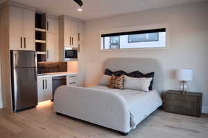 Bedroom featuring freestanding refrigerator, light wood-style floors, and recessed lighting