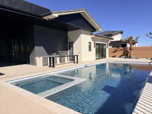 Integrated pool / hot tub featuring area for grilling and a patio area