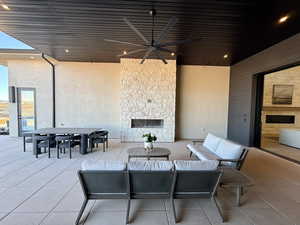View of patio featuring a ceiling fan, an outdoor living / dining area, and an outdoor stone fireplace