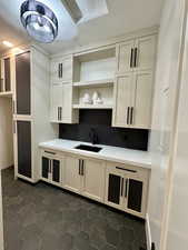 Kitchen featuring open shelves, decorative backsplash, light stone counters, white cabinets, and dark tile patterned floors