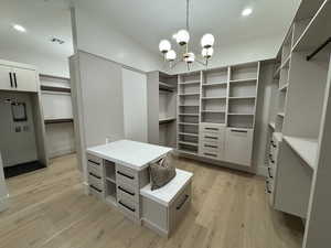 Walk in closet with a chandelier and light wood-type flooring