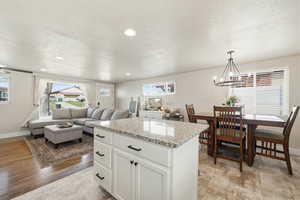 Kitchen with a kitchen island, white cabinets, light stone countertops, a textured ceiling, and open floor plan