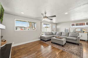 Living area featuring recessed lighting, dark wood-style flooring, a textured ceiling, and ceiling fan