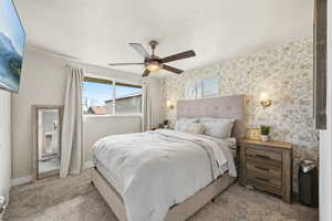 Carpeted bedroom featuring a textured ceiling, ceiling fan, and wallpapered walls