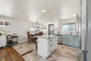 Kitchen with stainless steel appliances, a kitchen breakfast bar, backsplash, light stone countertops, and a kitchen island