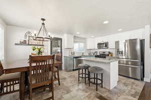 Kitchen featuring stainless steel appliances, light stone countertops, a center island, tasteful backsplash, and white cabinets