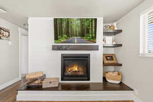 Detailed view of a fireplace, wood finished floors, and a textured ceiling
