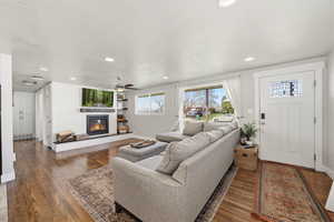 Living room featuring a glass covered fireplace, dark wood finished floors, recessed lighting, and a ceiling fan