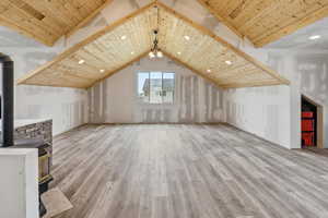 Additional living space featuring a wood stove, a wooden ceiling with exposed beams, light wood-style flooring, and recessed lighting