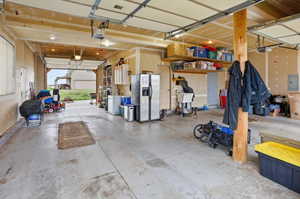 Attached Garage with stainless steel fridge, electric panel, white fridge, and a garage door opener