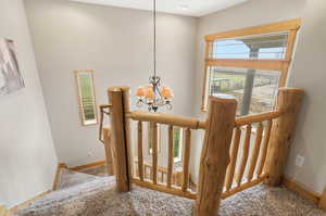 Stairs featuring hanging lights, plenty of natural light, and carpet