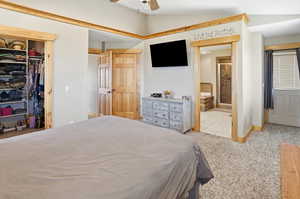 Primary Bedroom with vaulted ceiling, a ceiling fan, light carpet, a walk-in closet, and ensuite bathroom