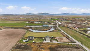 Aerial view of property and surrounding area with rural landscape, a mountainous background, and rows of crops