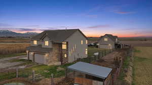 View of front facade featuring stone siding, an outdoor structure, driveway, roof with shingles, and a garage