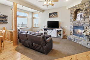 Living room featuring ceiling fan, a stone fireplace, wood finished floors, and recessed lighting