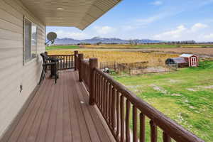 Wooden terrace with a yard, a view of countryside, a mountain view, and an outbuilding