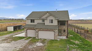 View of front of home featuring roof with shingles, a view of countryside, an attached garage, and driveway