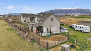 Rear view of property with a mountain view, an attached garage, a shingled roof, an outdoor structure, and driveway