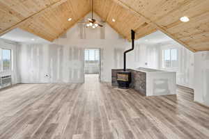 Unfurnished living room featuring a high wooden ceiling, a wood stove, recessed lighting, light wood-type flooring, and ceiling fan