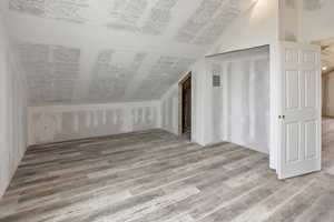 Additional living space with vaulted ceiling and light wood-style floors