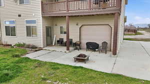 Back of house featuring a patio area, a lawn, an attached garage, and an outdoor fire pit