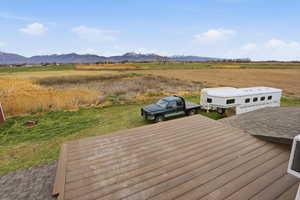 Wooden terrace with a view of countryside, a mountain view, and a yard