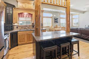 Two tone kitchen featuring backsplash, a kitchen bar, a center island, dark stone counters, and open floor plan