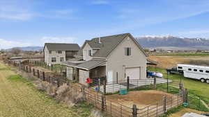 Back of property featuring a mountain view, roof with shingles, an attached garage, a rural view, and an outdoor structure