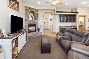 Living area with ceiling fan and a stone fireplace