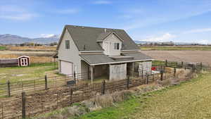 View of side of property with a shingled roof, an outdoor structure, a mountain view, a rural view, and a garage