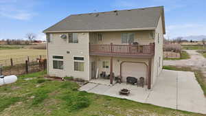 Rear view of property featuring a patio, an attached garage, a shingled roof, driveway, and a wooden deck