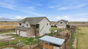 View of side of home featuring a shingled roof, stone siding, a view of countryside, and driveway