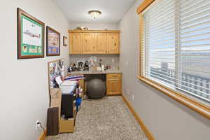 Office area featuring light colored carpet, built in study area, and a textured ceiling