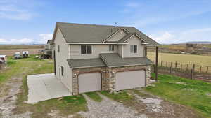 View of front of home featuring a shingled roof, a mountain view, driveway, a rural view, and an attached garage