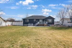 Rear view of house with a fenced backyard, a deck, roof with shingles, and a patio area