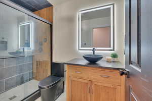 Bathroom featuring vanity, a shower stall, and a textured wall