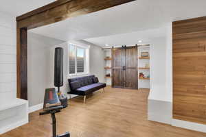 Sitting room with a barn door, light wood finished floors, and wood walls