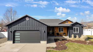 View of front of property featuring board and batten siding, a garage, a porch, and concrete driveway
