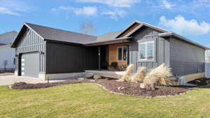 View of front of home featuring a garage, a front yard, driveway, and roof with shingles