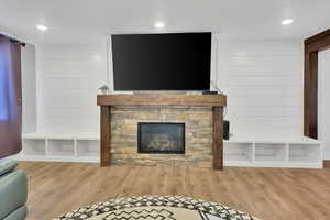 Living room with wood finished floors, wood walls, a fireplace, and recessed lighting