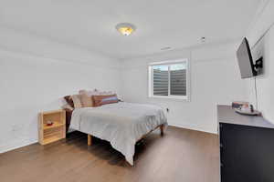Bedroom with wood finished floors and ornamental molding