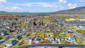 Aerial view of residential area featuring property boundaries highlighted and a mountain backdrop