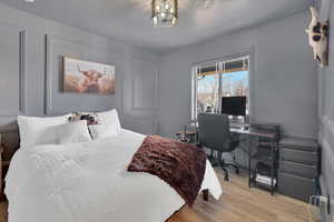 Bedroom featuring an office area, a decorative wall, and wood finished floors