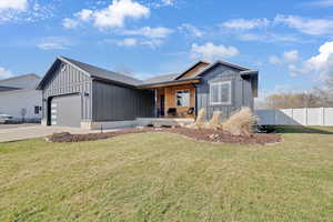 View of front of house featuring board and batten siding, an attached garage, and driveway
