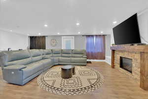 Living area featuring light wood-style floors, a stone fireplace, and recessed lighting