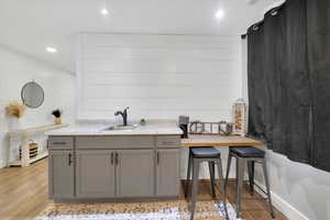 Kitchen featuring gray cabinetry, light wood finished floors, wooden counters, recessed lighting, and wood walls