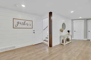 Foyer entrance with light wood-type flooring, recessed lighting, and wood walls