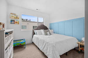 Bedroom with decorative wainscoting, large window for natural light, and walk in closet.